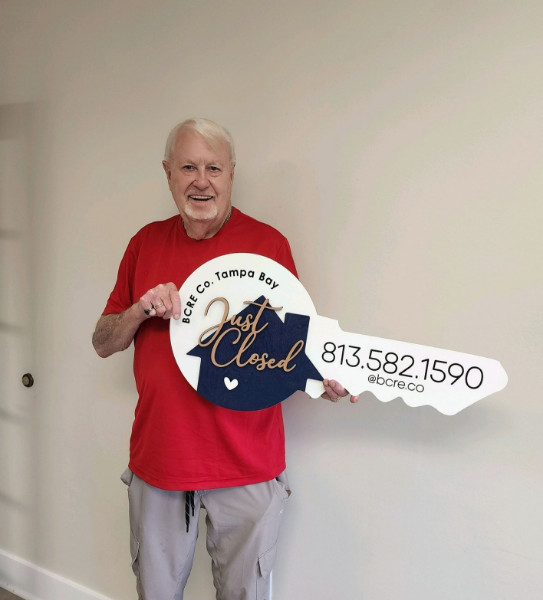 A man holding up a large key to his new home.