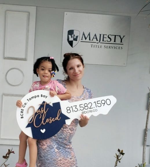 A woman holding a sign with a child in front of it.