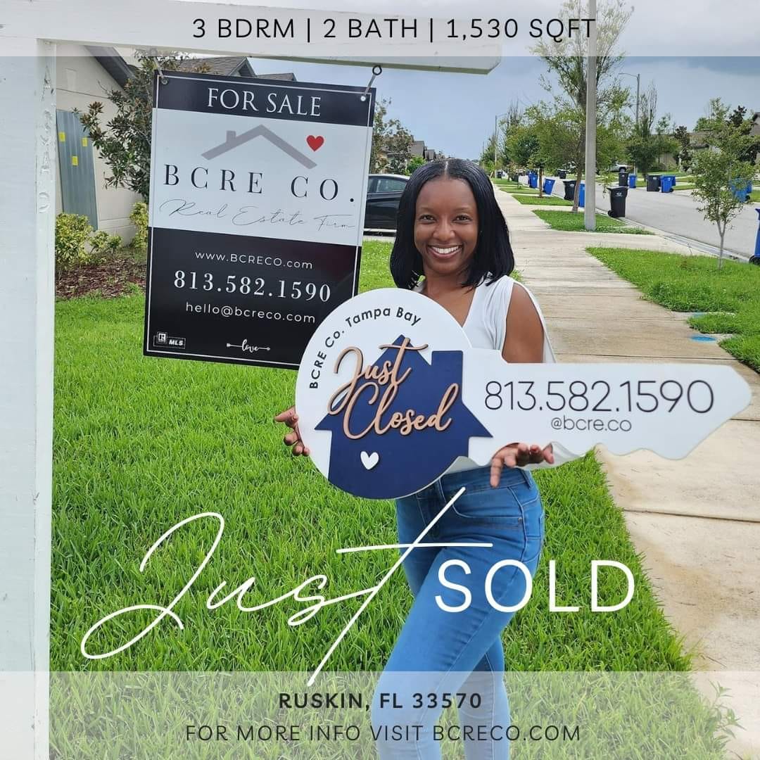 A woman holding an arrow sign in front of some houses.