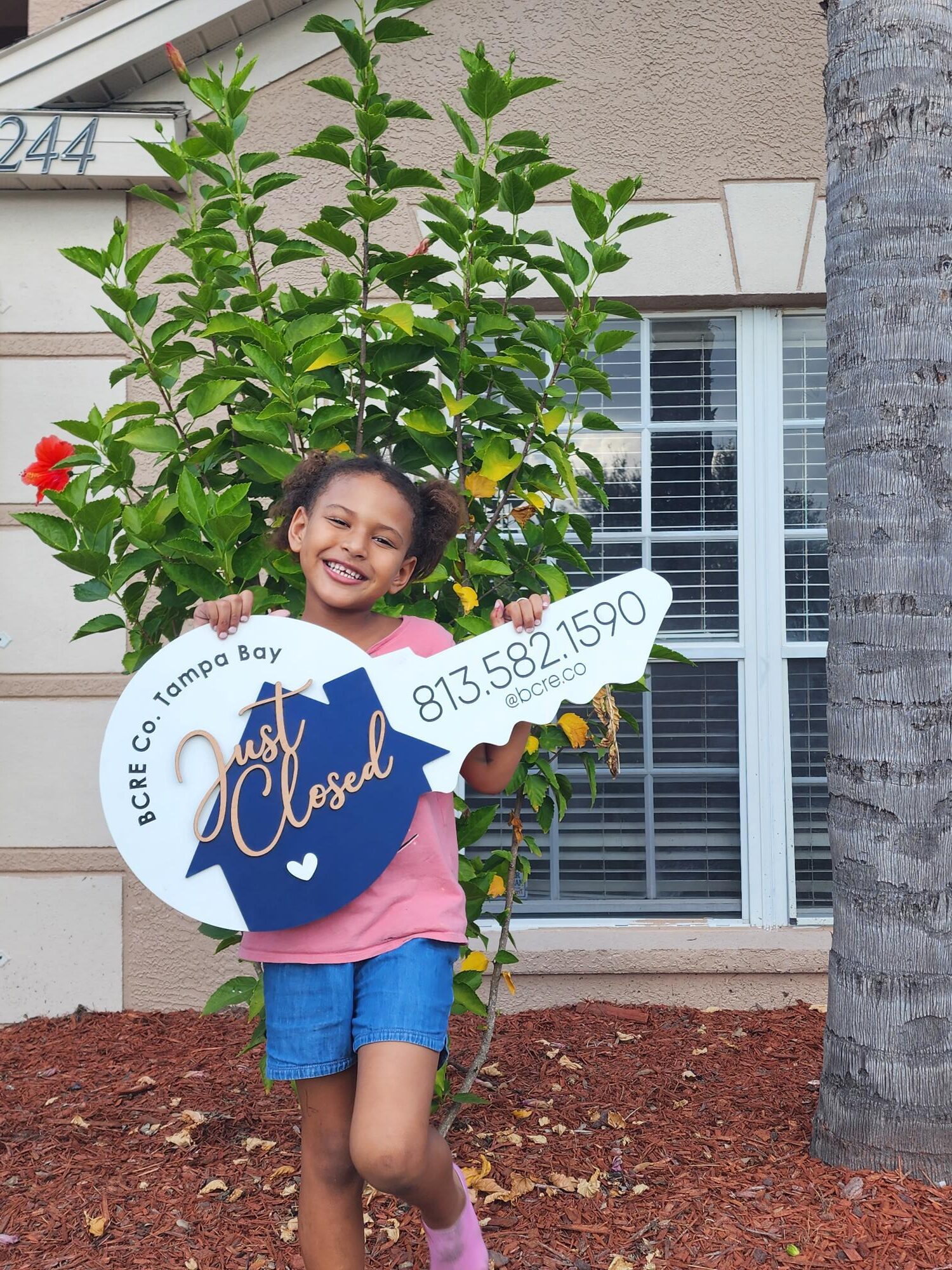 A little girl holding up a key shaped sign.